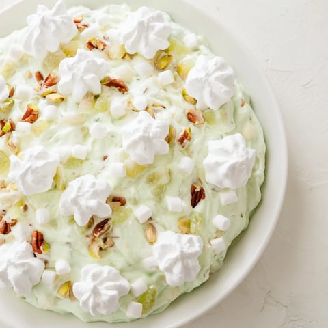 Creamy Watergate Salad with bright green hue, marshmallows, and pecans, perfect for bringing to a picnic.