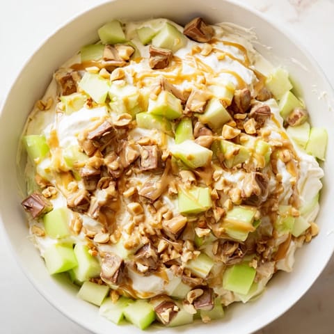 This colorful Snickers Salad includes diced apples, Snickers, and a smooth, vanilla pudding base.