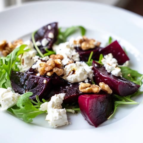 Roasted beet goat cheese salad arranged with jewel-toned beets, creamy crumbles, and walnuts over arugula on a rustic table.
