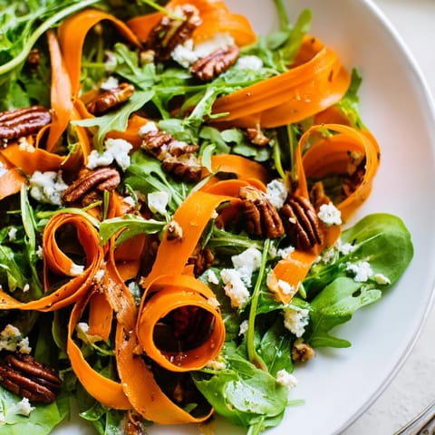 Tender, caramelized carrot ribbons arranged over arugula and spinach, topped with feta and pecans for a fresh Roasted Carrot Ribbon Salad.