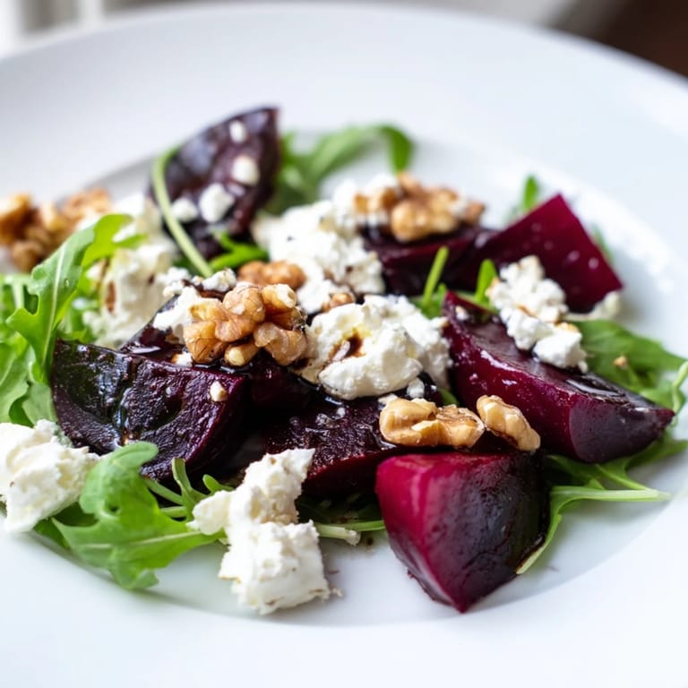 Roasted beet goat cheese salad arranged with jewel-toned beets, creamy crumbles, and walnuts over arugula on a rustic table.