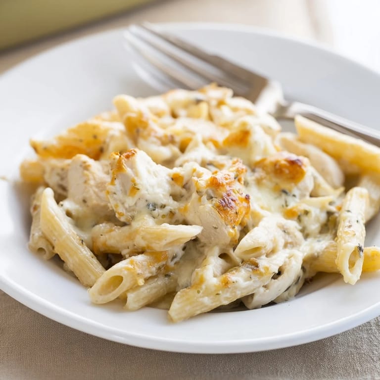 A spoon lifts creamy Chicken Ranch Pasta Bake with chicken, pasta, and ranch sauce.