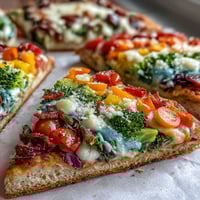 Vibrant St. Patrick's Day Rainbow Veggie Flatbread Pizza with fresh vegetables arranged in colorful layers on crispy crust.  